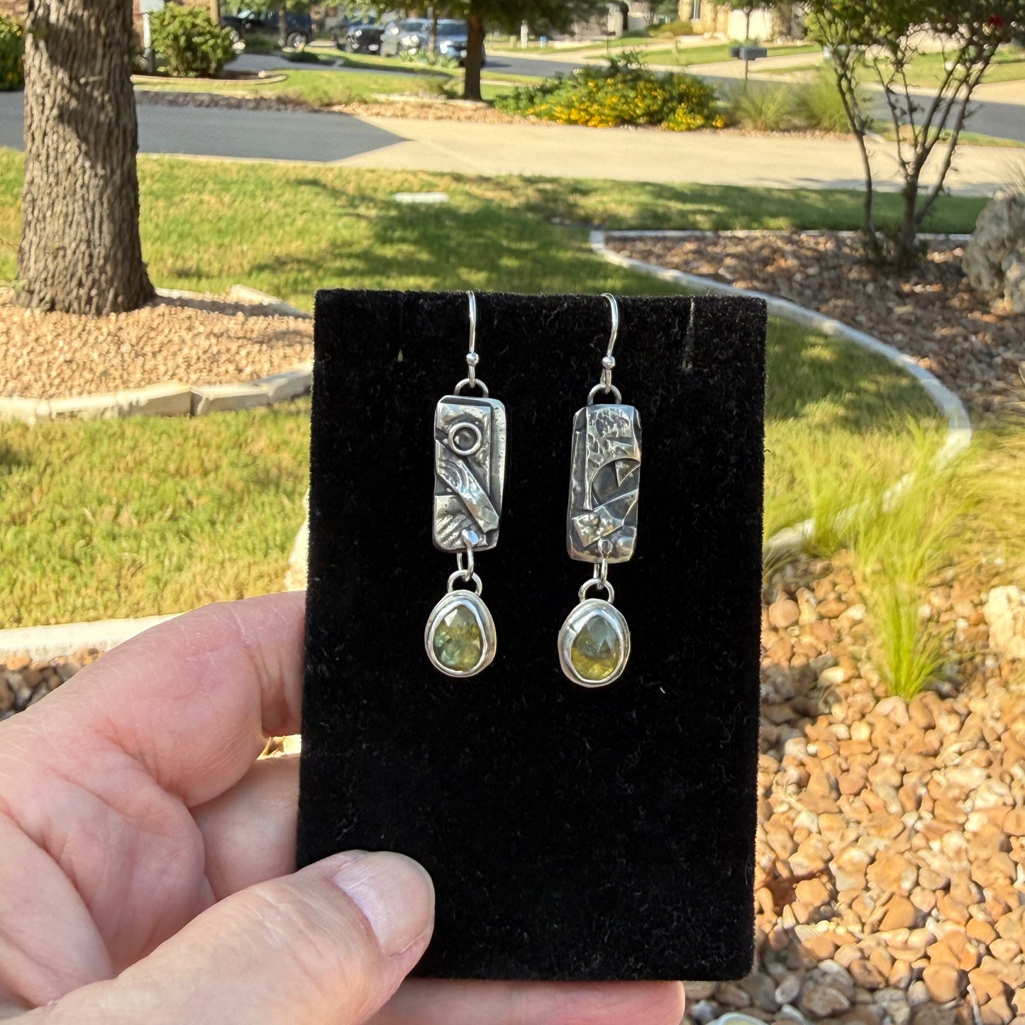 Parti sapphire and patchwork silver dangle earrings on black velvet display card outdoors