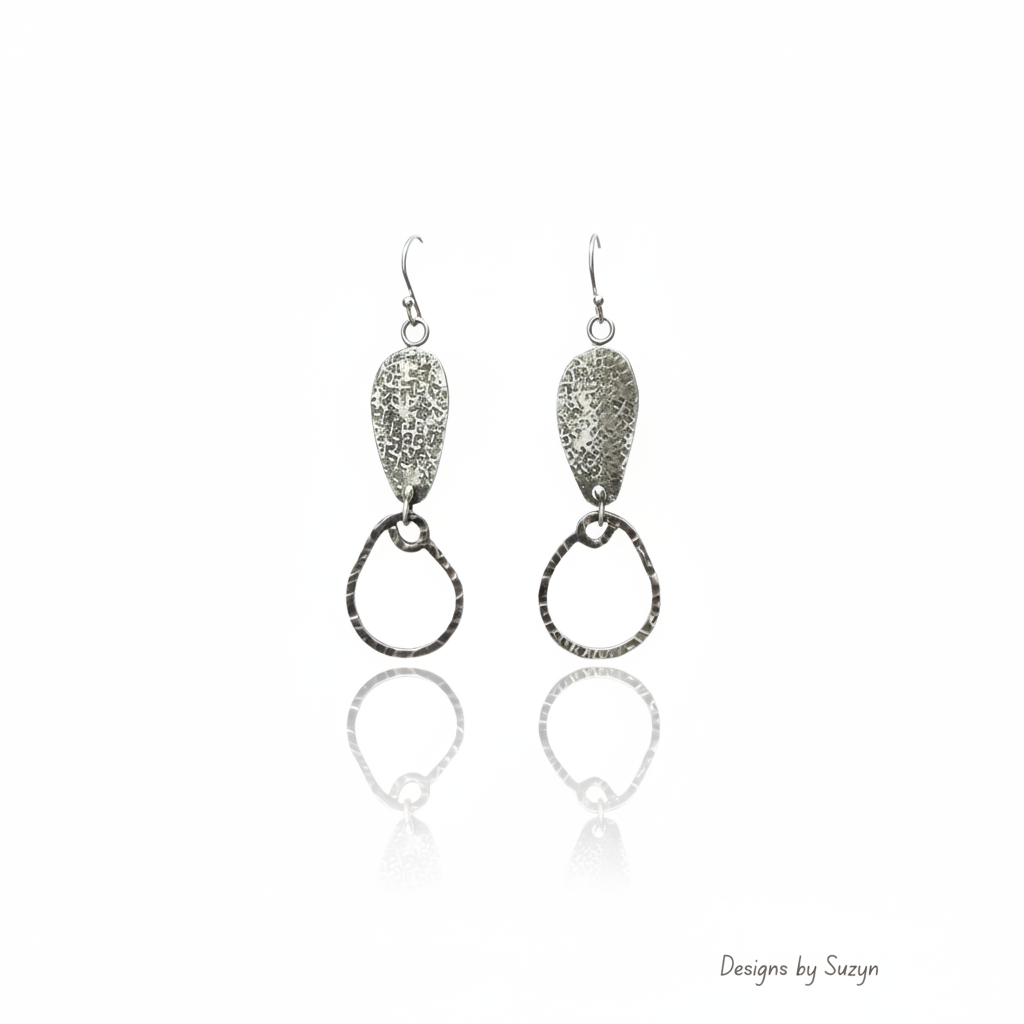 Silver textured teardrop and hammered hoop dangle earrings on white reflective background