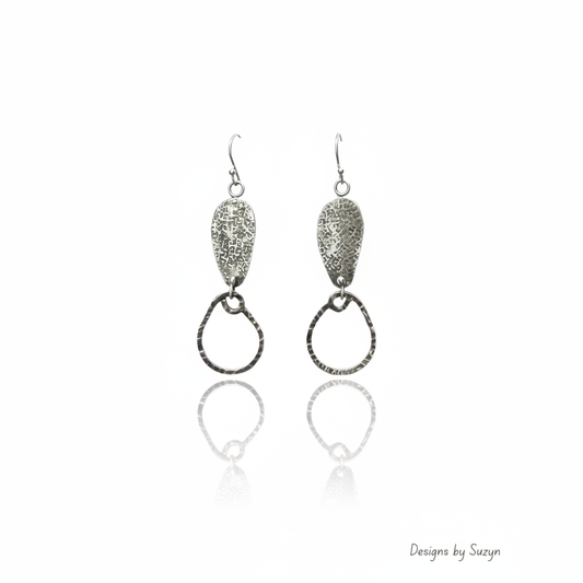 Silver textured teardrop and hammered hoop dangle earrings on white reflective background