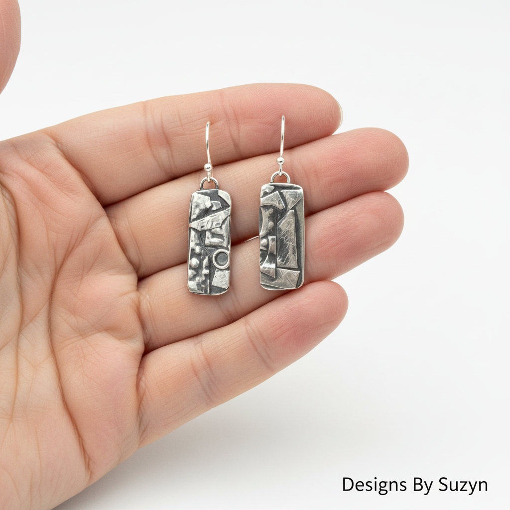Scale reference photo of hand-etched Argentium silver botanical dangle earrings in palm of hand